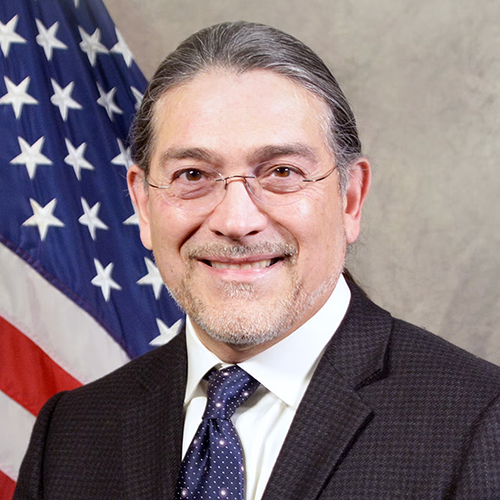 Official photograph of US Census Bureau director Robert Santos, with US flag in background.