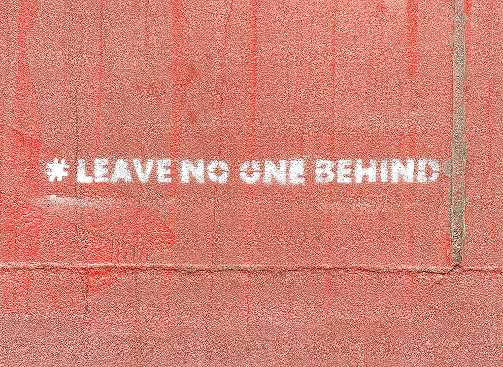Wall stencilled with the phrase '# Leave no one behind'.