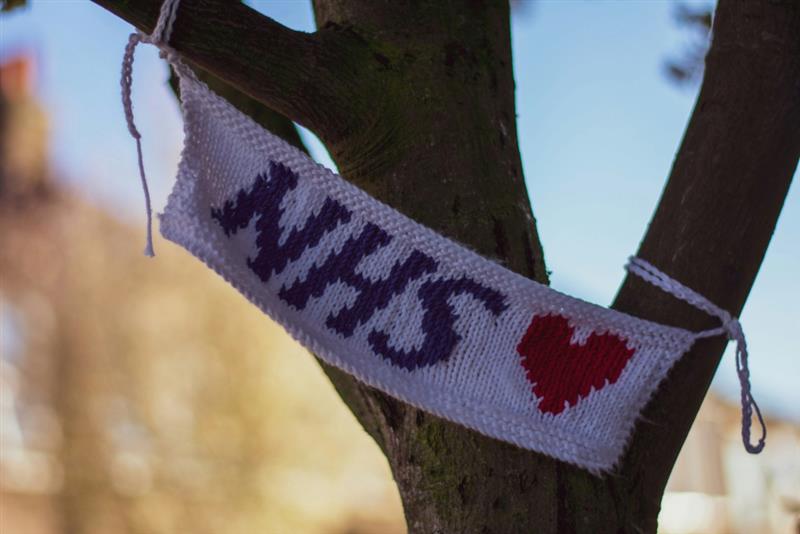 An image of a croched NHS flag attached to a tree